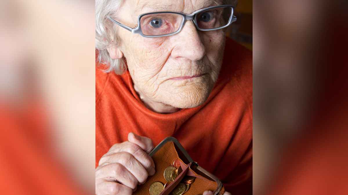 Mujer mayor sostiene un monedero con pocas monedas tras perder pensión por error de la Seguridad Social
