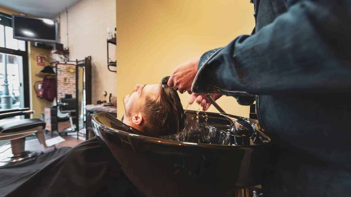hombre lavándose el pelo en peluquería antes de corte por norma de higiene