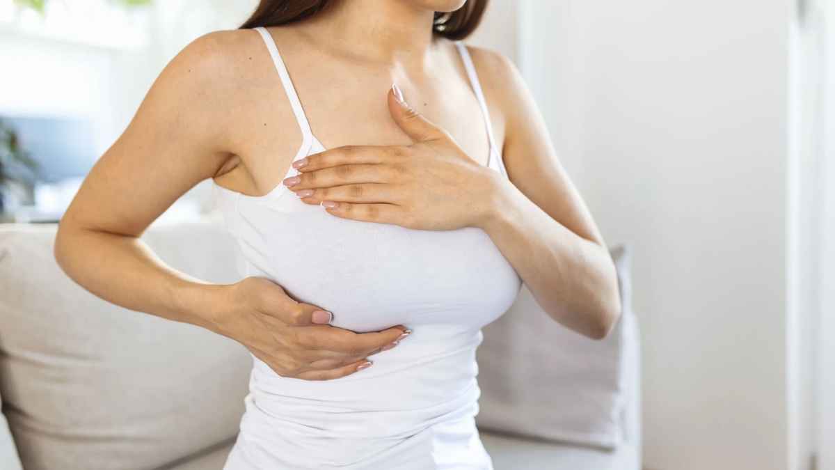 Mujer con cáncer de mama tocándose el pecho durante autoexploración