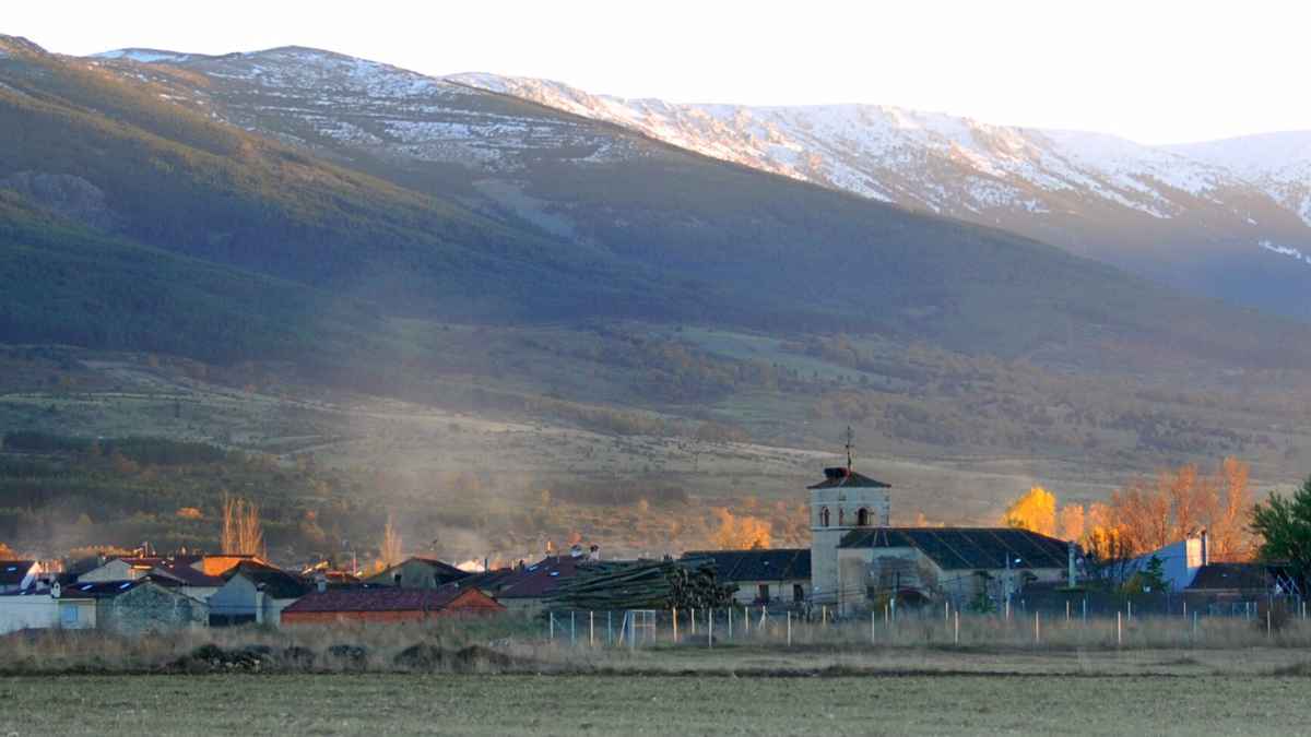 Vista del pueblo rural de Prádena en Segovia con montañas nevadas al fondo