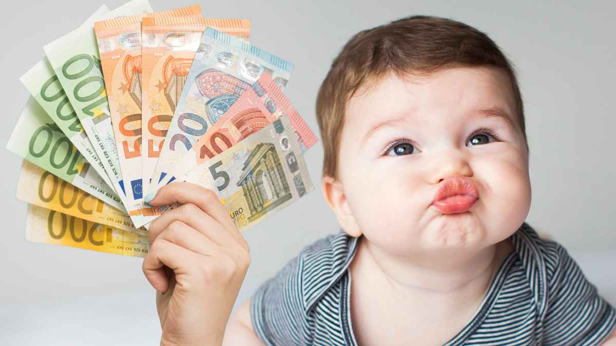 Bebé con dinero en mano como ejemplo de ayudas por nacimiento y paro suspendido por el SEPE