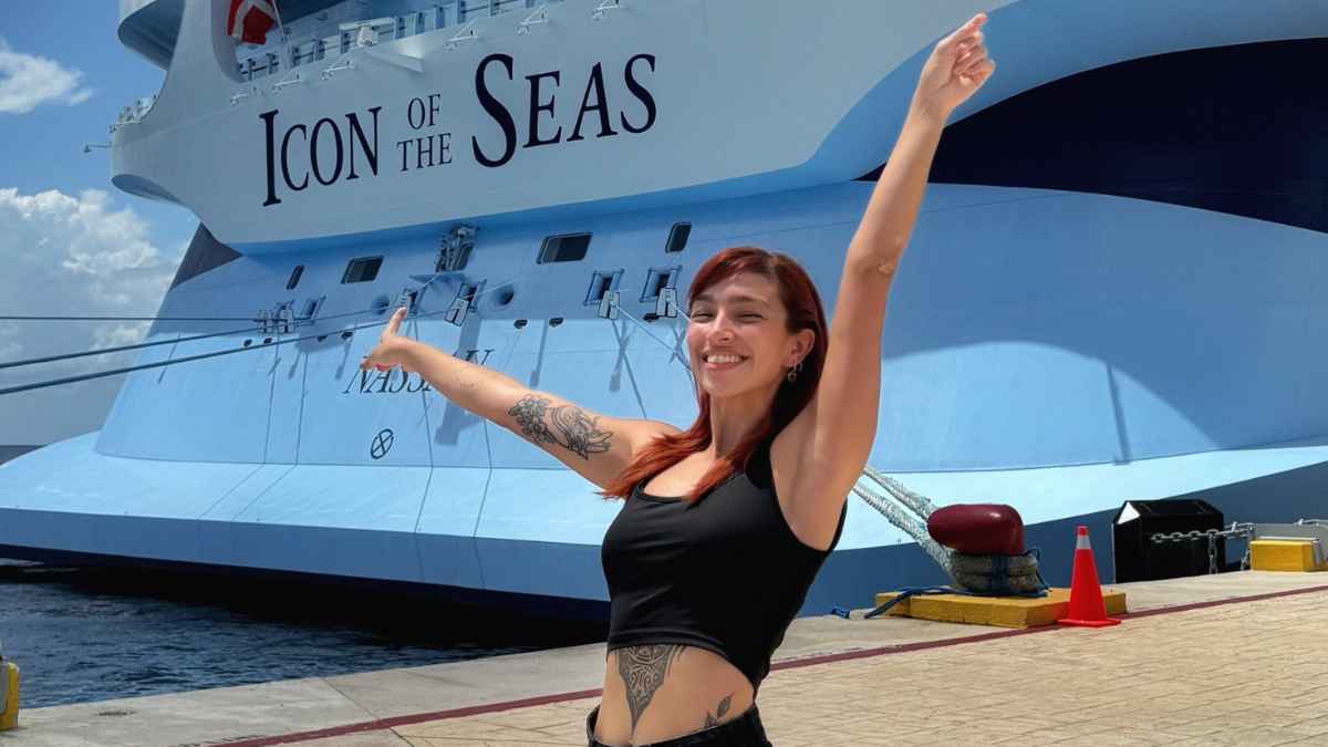 Tripulante de crucero sonriente delante del barco Icon of the Seas contando su experiencia de vivir seis meses navegando.