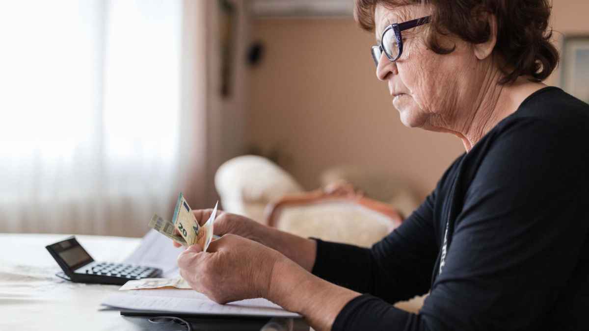Mujer jubilada contando dinero en casa preocupada por su pensión