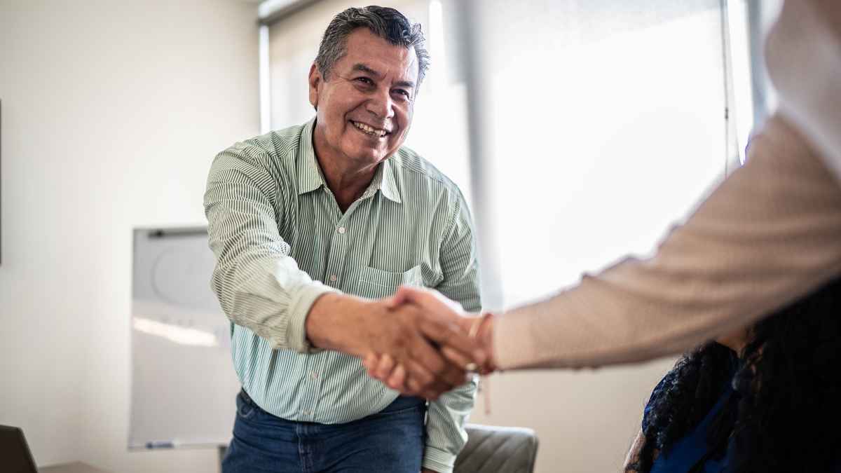Hombre mayor de 45 años estrechando la mano tras conseguir empleo