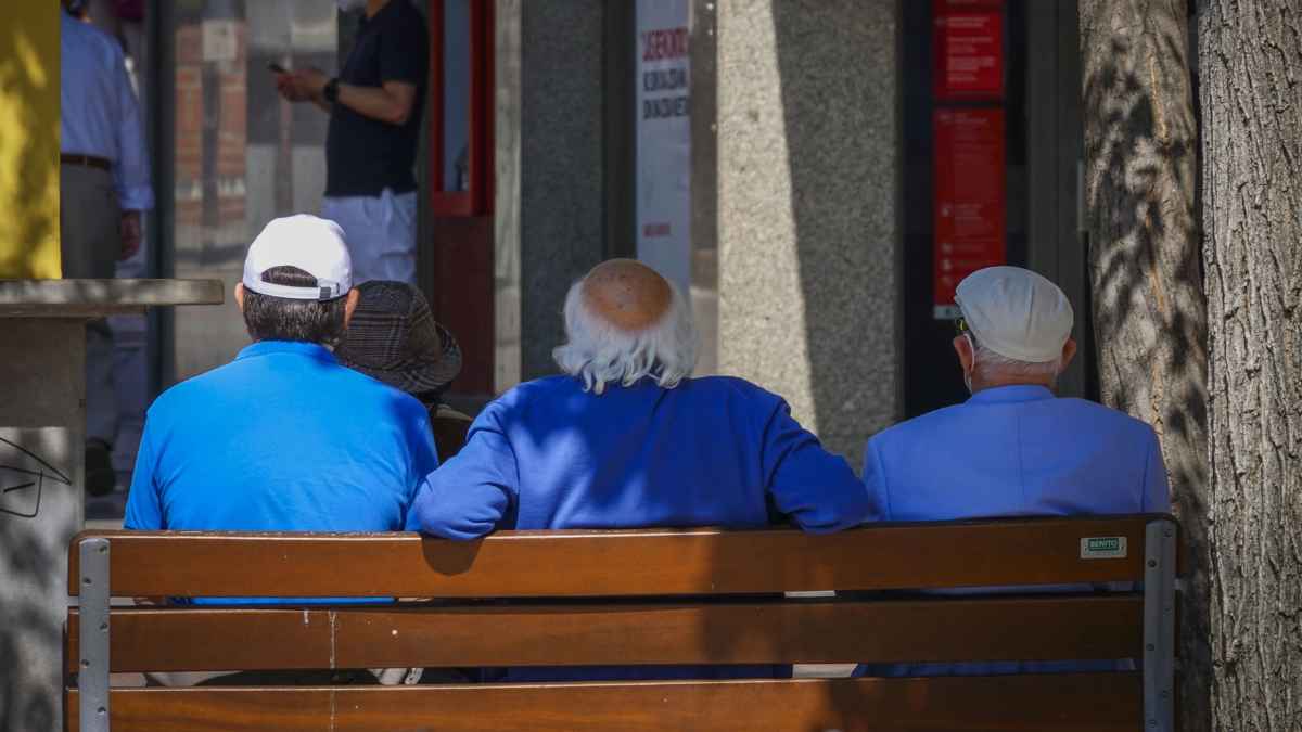Personas mayores sentadas en un banco representando la edad de jubilación en España