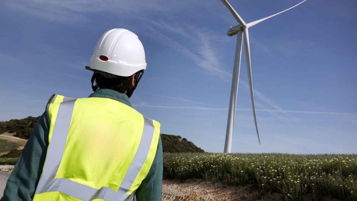 Trabajador observa aerogenerador en proyectos de energía eólica
