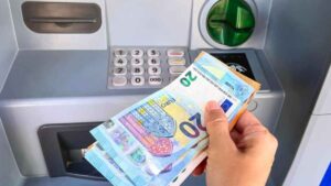 Persona sacando dinero en efectivo de un cajero automático con billetes de euro