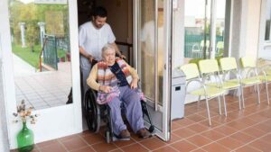Trabajador de residencia ayudando a persona mayor en silla de ruedas