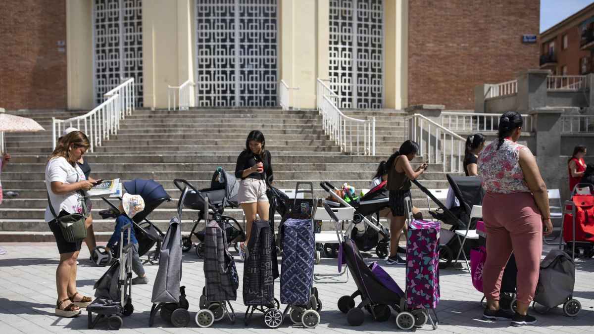 Familias con carritos en España esperando ayudas sociales públicas