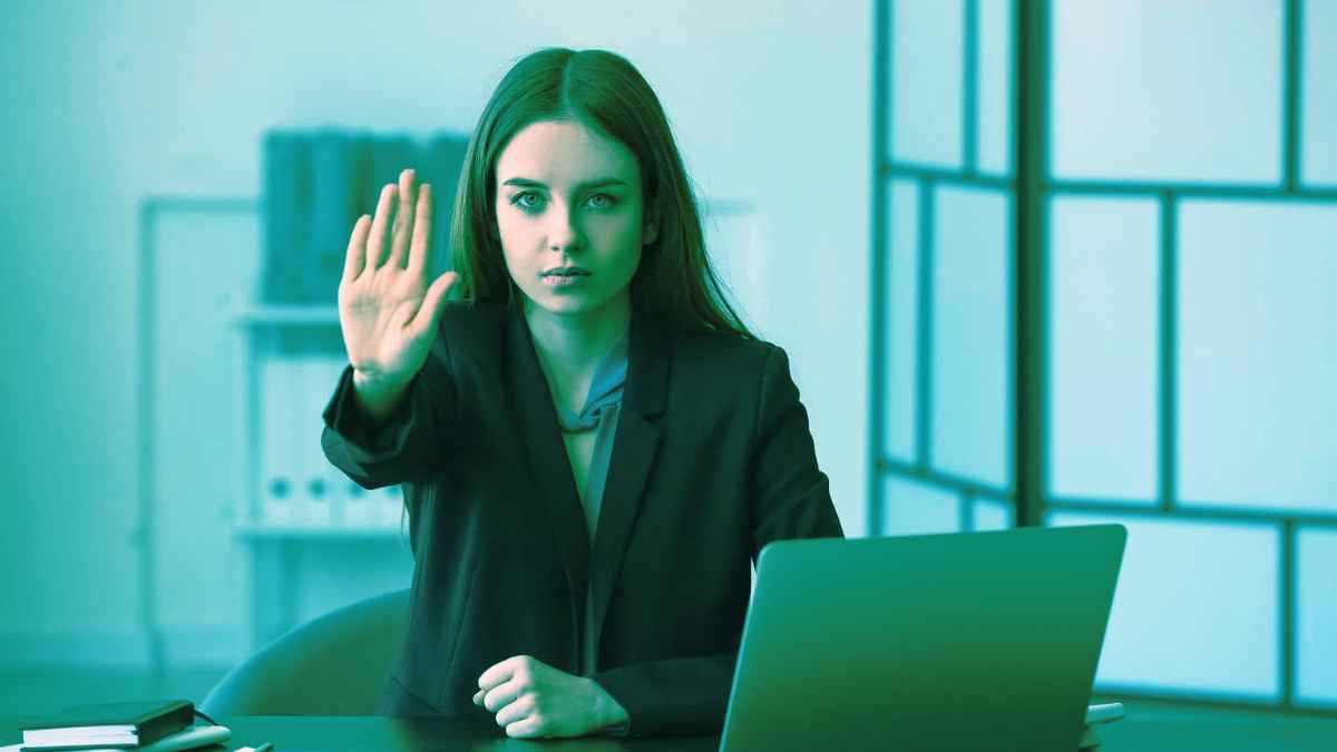 Mujer en oficina deteniéndose como símbolo de defensa ante la ley del hielo en el trabajo