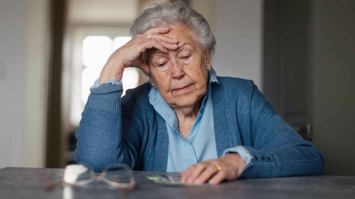 Mujer mayor preocupada revisando dinero, pensión no contributiva en Madrid con complemento de 1050 euros en 2026