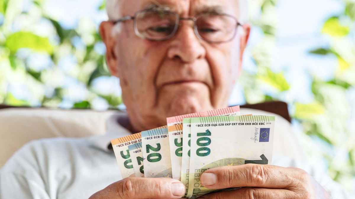 Hombre mayor contando billetes por paga mensual de pensión no contributiva de la Seguridad Social