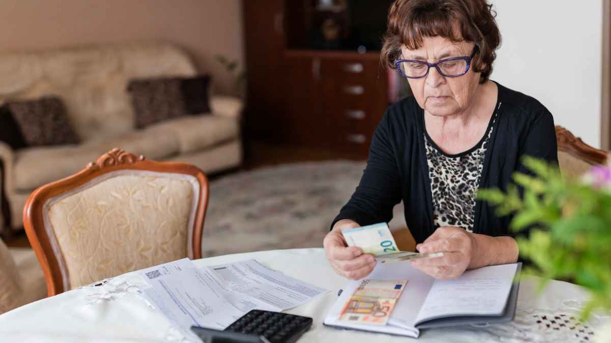 Mujer jubilada contando dinero en casa con pensión no contributiva en Madrid