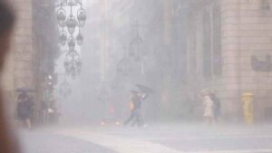 Personas con paraguas caminando bajo lluvias torrenciales en alerta roja en España