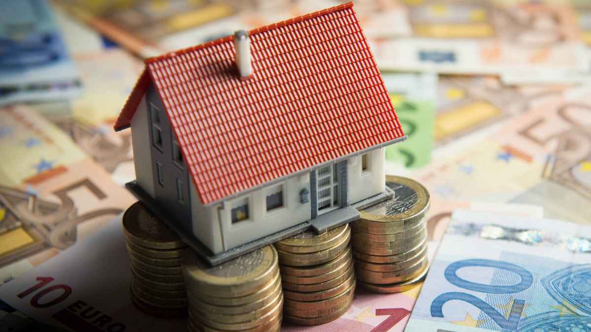 Casa sobre monedas y billetes para reclamar gastos de hipoteca