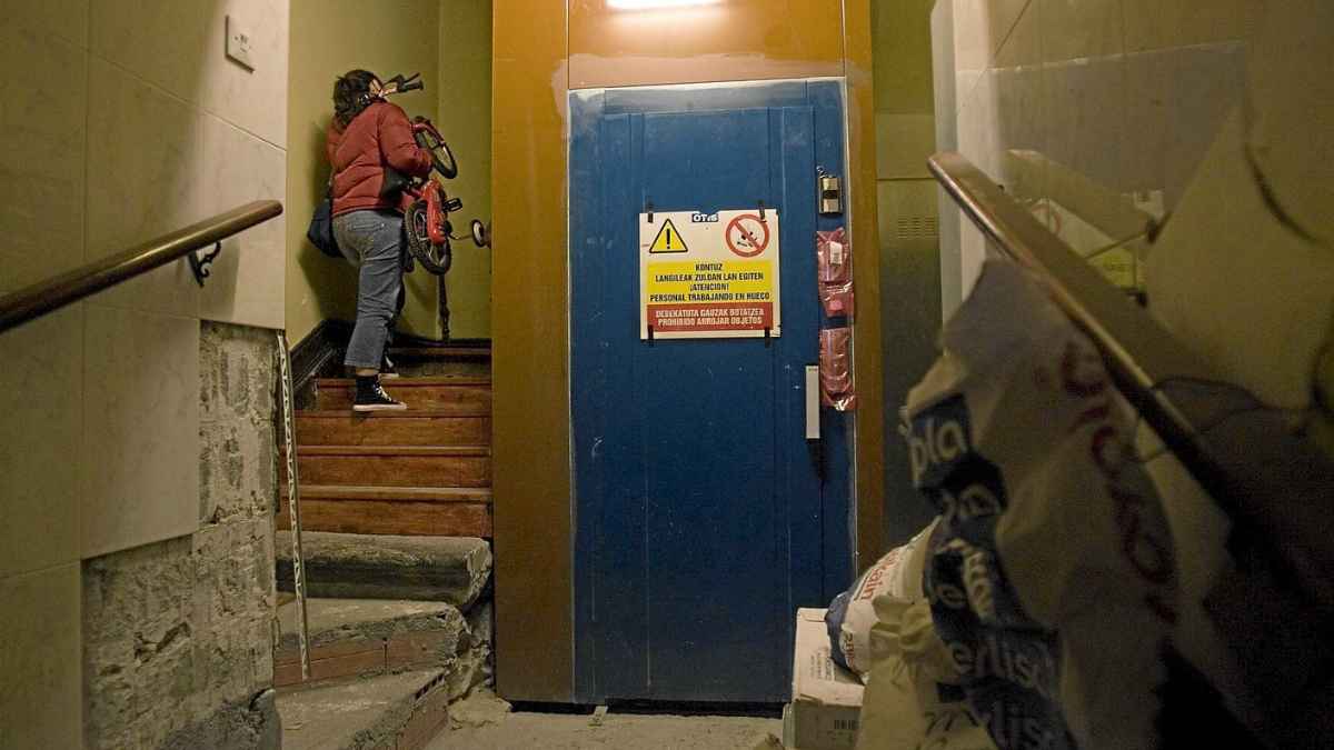 vecina subiendo escaleras en comunidad con ascensor en obras
