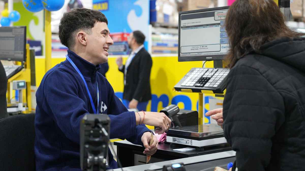 Empleado de Carrefour atendiendo a una clienta en caja dentro de un supermercado