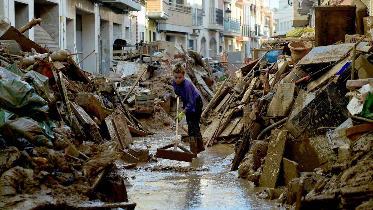 Persona limpiando una calle tras una inundación, ejemplo de prevención ante catástrofes naturales en el curso gratuito online de la Generalitat.