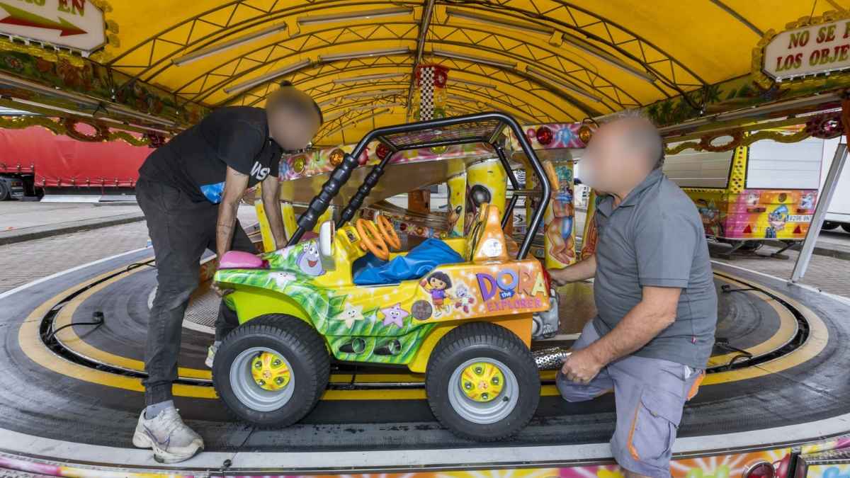 Feriantes montando una atracción infantil en la feria durante su jornada de trabajo