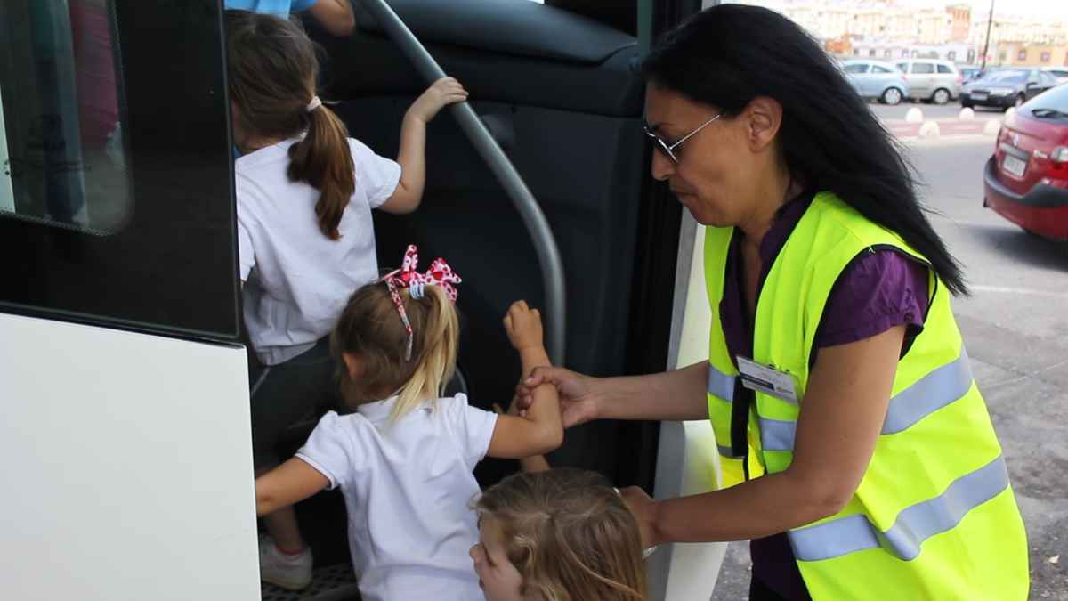 Monitora ayuda a niños a subir al autobús escolar en Granada durante el curso 2025-2026