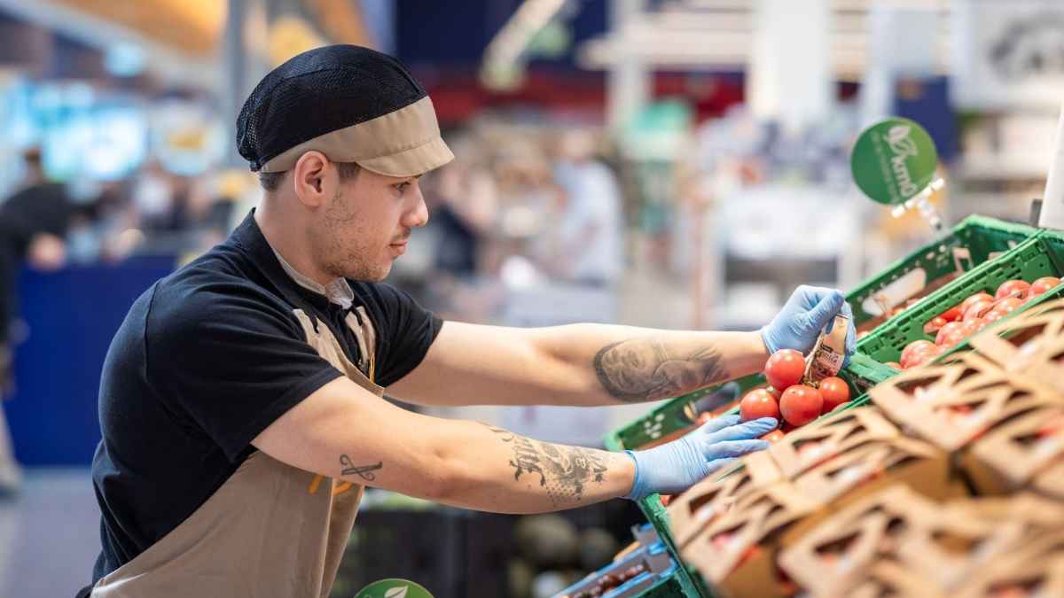 Empleado de Bon Preu en Terrassa colocando tomates en el supermercado durante su turno intensivo rotativo