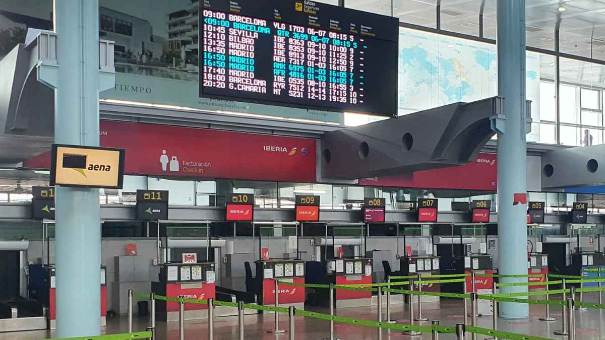 Mostrador de facturación de Iberia en el aeropuerto de Vigo con panel de salidas AENA