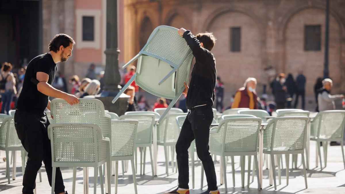 Trabajadores de hostelería colocando sillas en una terraza tras la subida del salario mínimo 2025