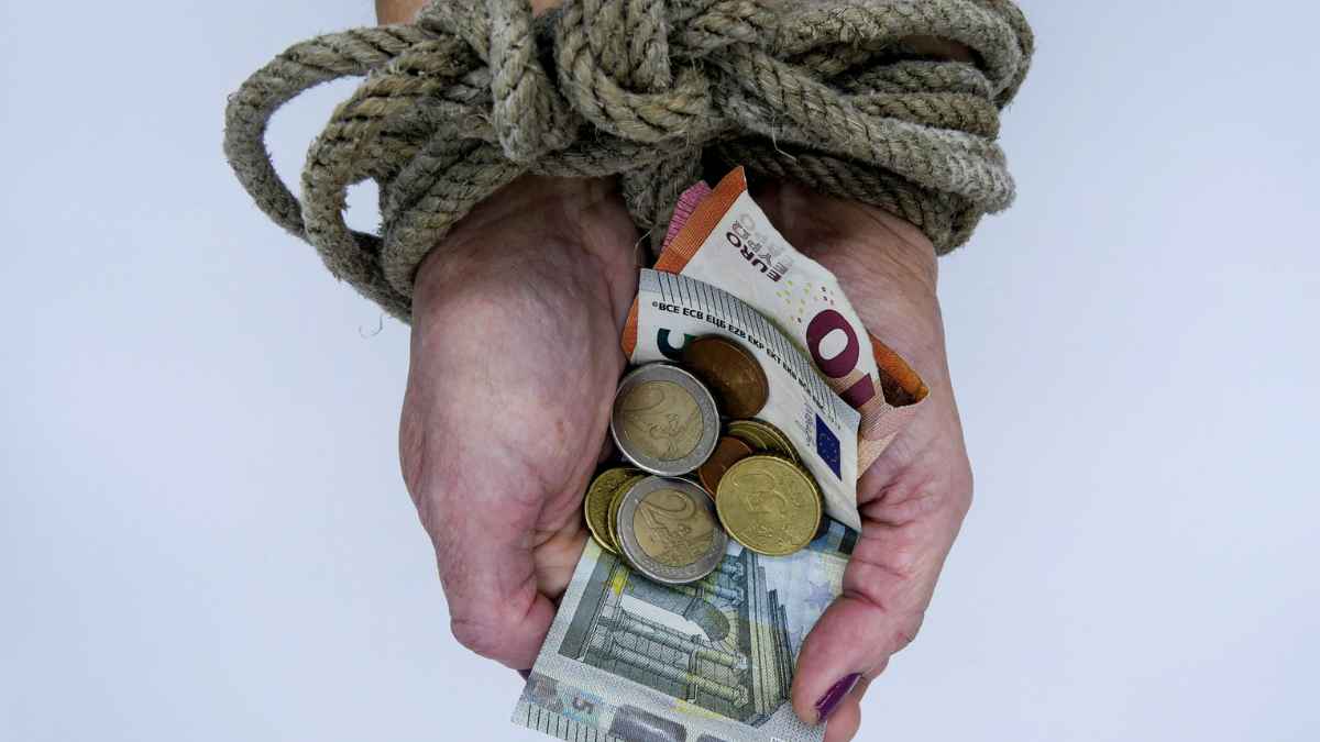 Manos atadas con cuerda sosteniendo dinero en euros que simbolizan la violencia económica reconocida por el Tribunal Supremo.