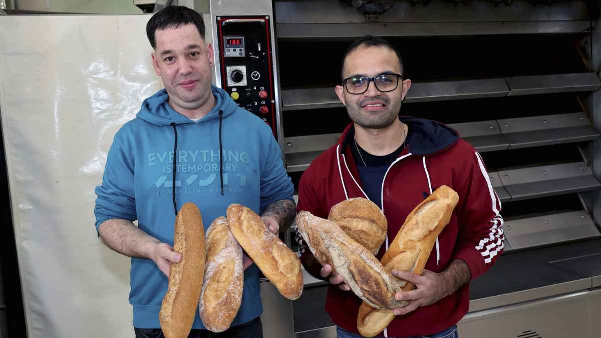 Trabajadores extranjeros en panadería en España mostrando barras de pan