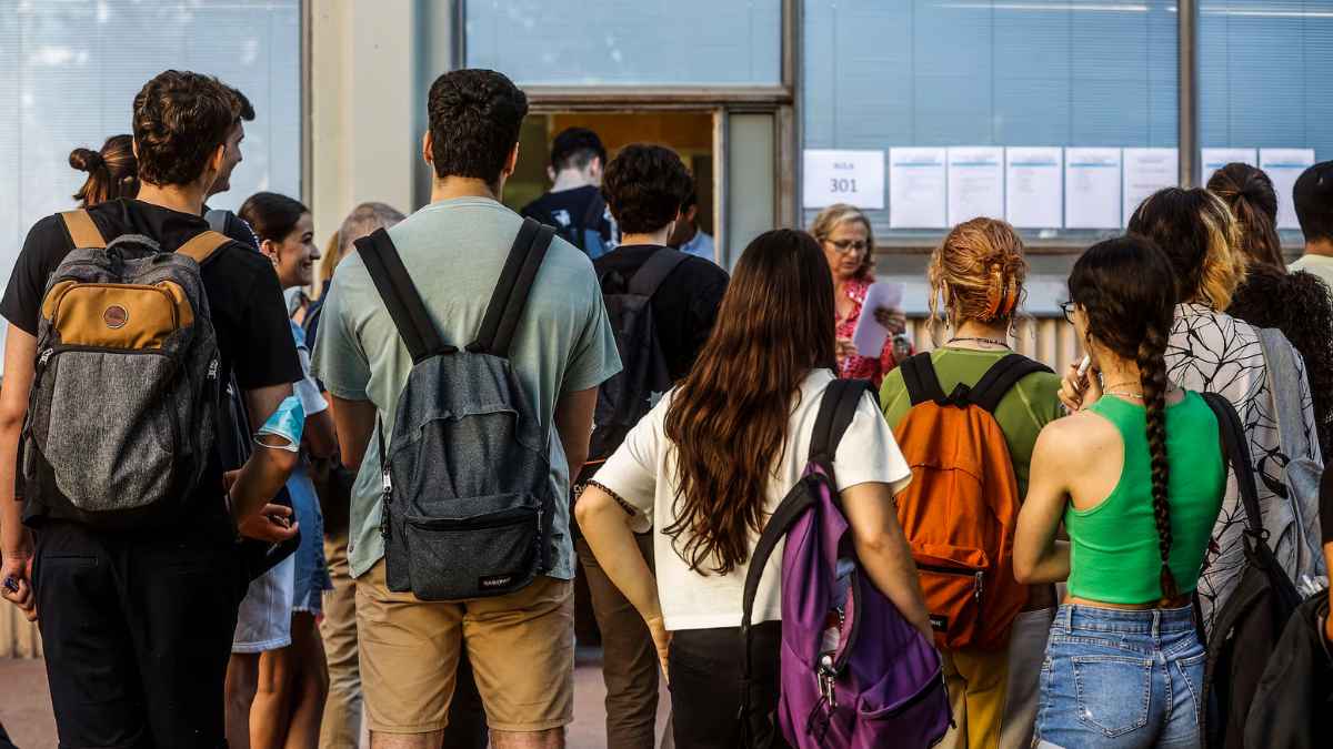 Estudiantes haciendo cola en un centro educativo para trámites académicos.