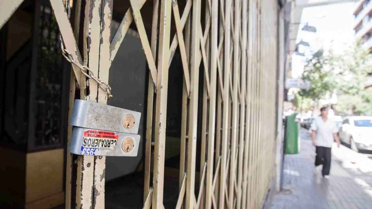 Reja de local comercial cerrado con candado en una calle urbana