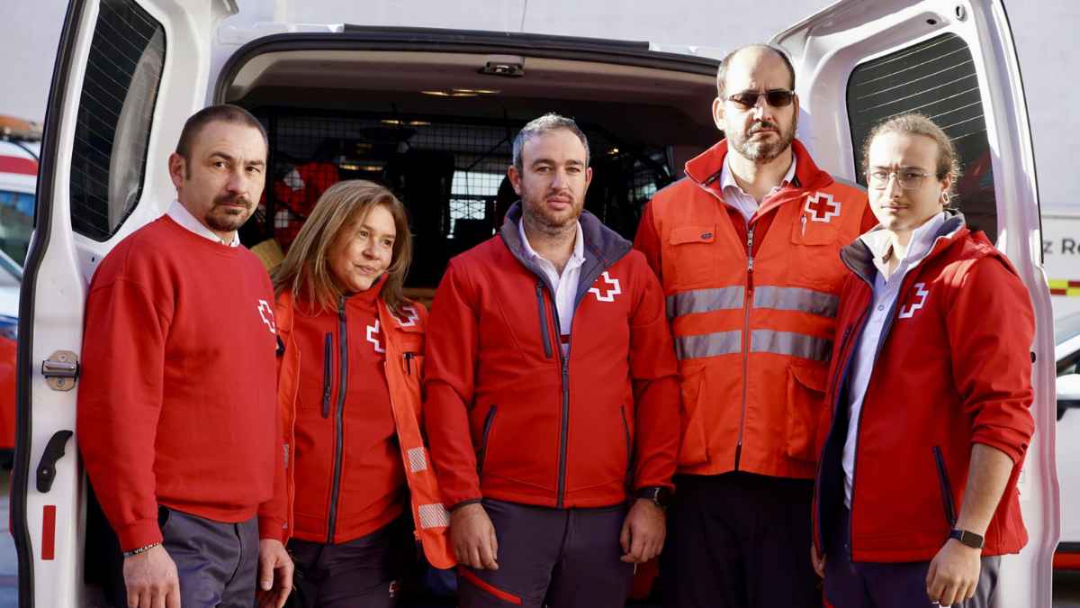 Equipo de Cruz Roja posando junto a un vehículo de emergencias.