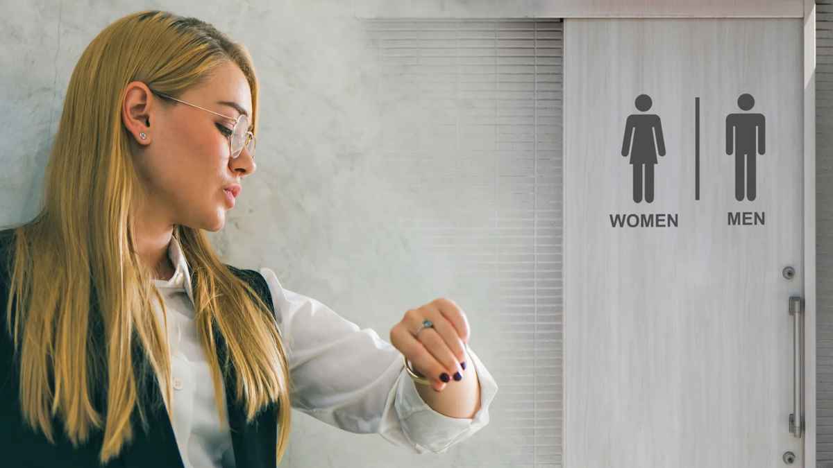 Empleado mirando la hora frente a la puerta del baño en un contexto laboral