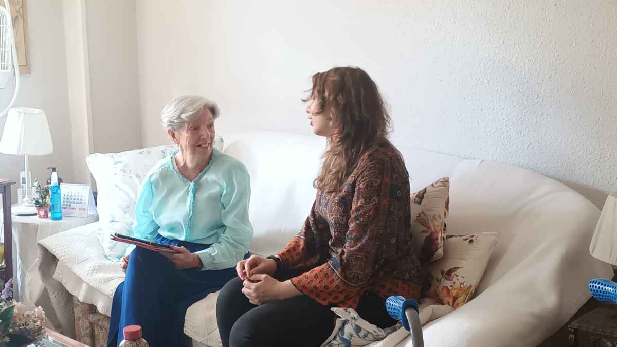 Mujer joven conversa con una persona mayor de 65 años en su casa para aplicar la deducción de Hacienda