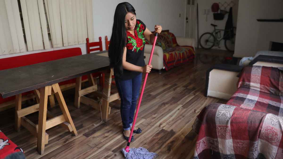Trabajadora del hogar limpiando el suelo en una vivienda, relacionada con el nuevo criterio del SEPE sobre periodos trabajados antes de 2022.