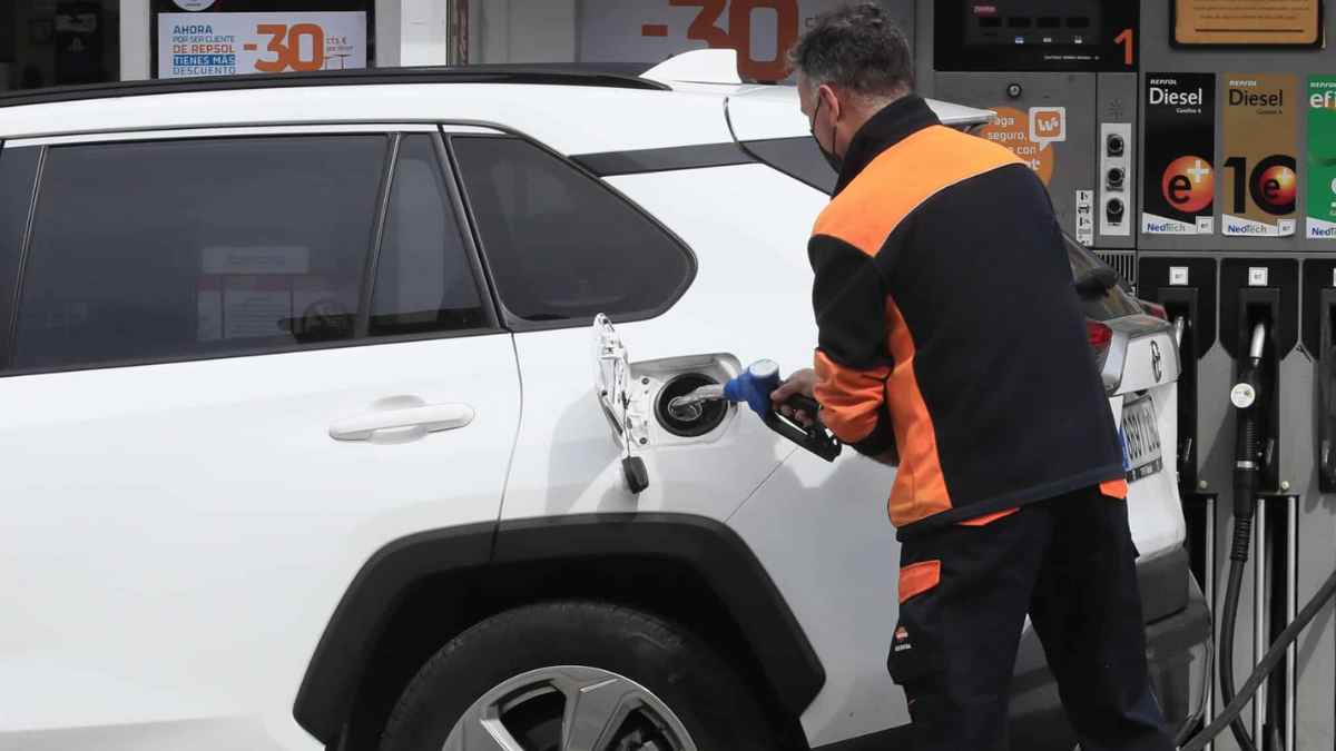 Trabajador repostando coche en estación de servicio durante su jornada laboral en gasolinera en España