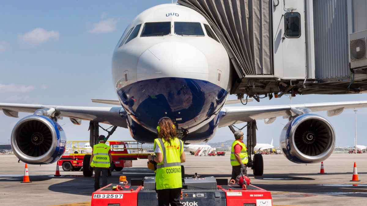 Personal de asistencia en tierra trabajando en un avión en un aeropuerto de Aena durante las operaciones en pista