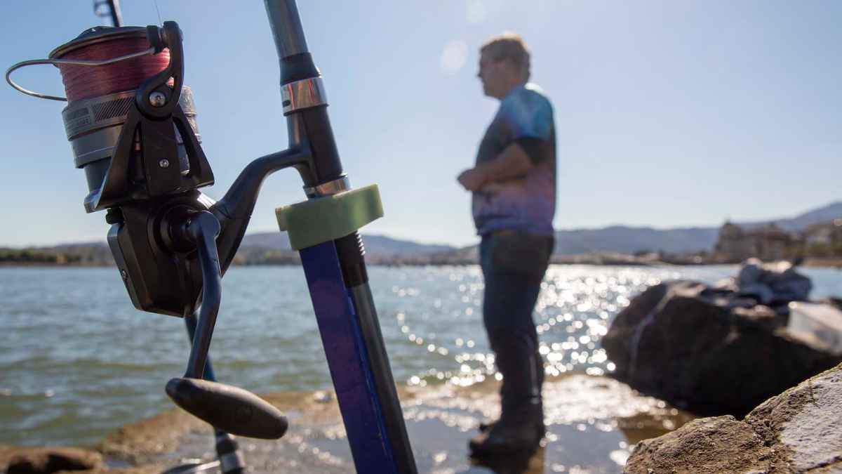 Pescador recreativo en la costa con caña de pescar junto al mar