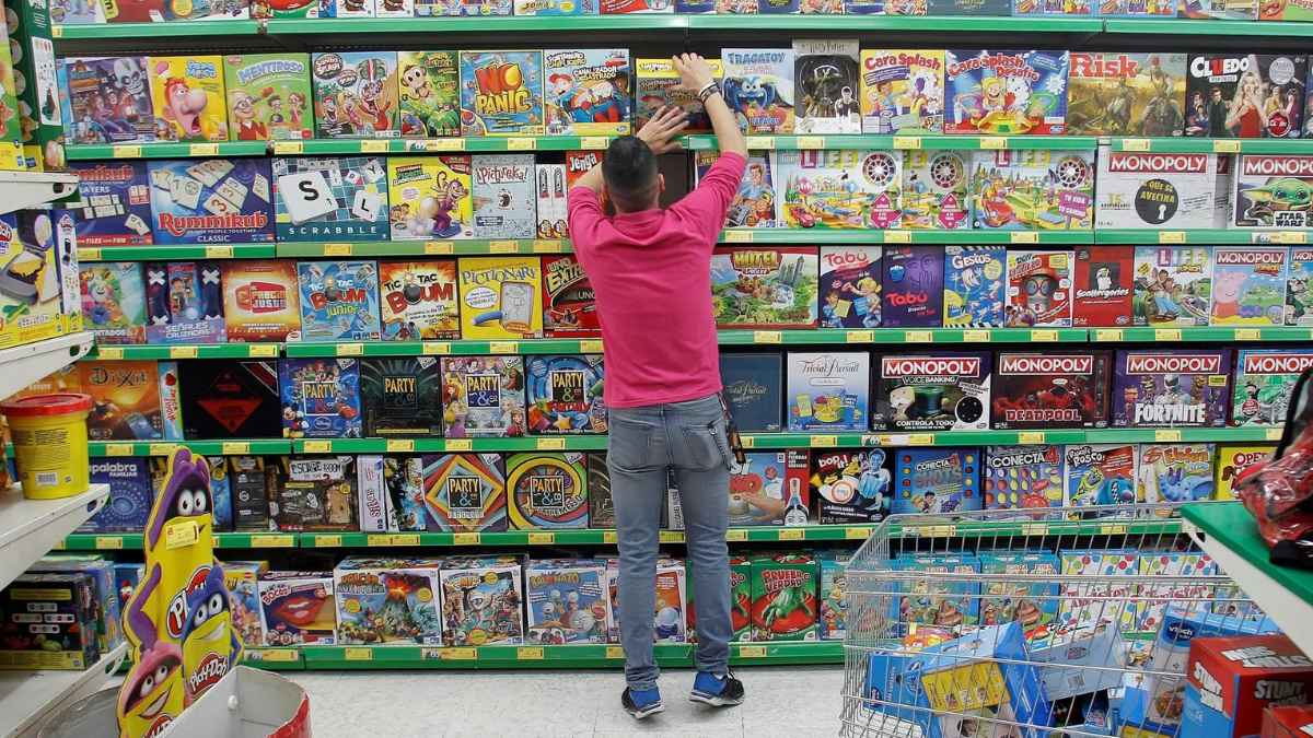 Empleado organizando estanterías de juegos de mesa en una tienda de juguetes