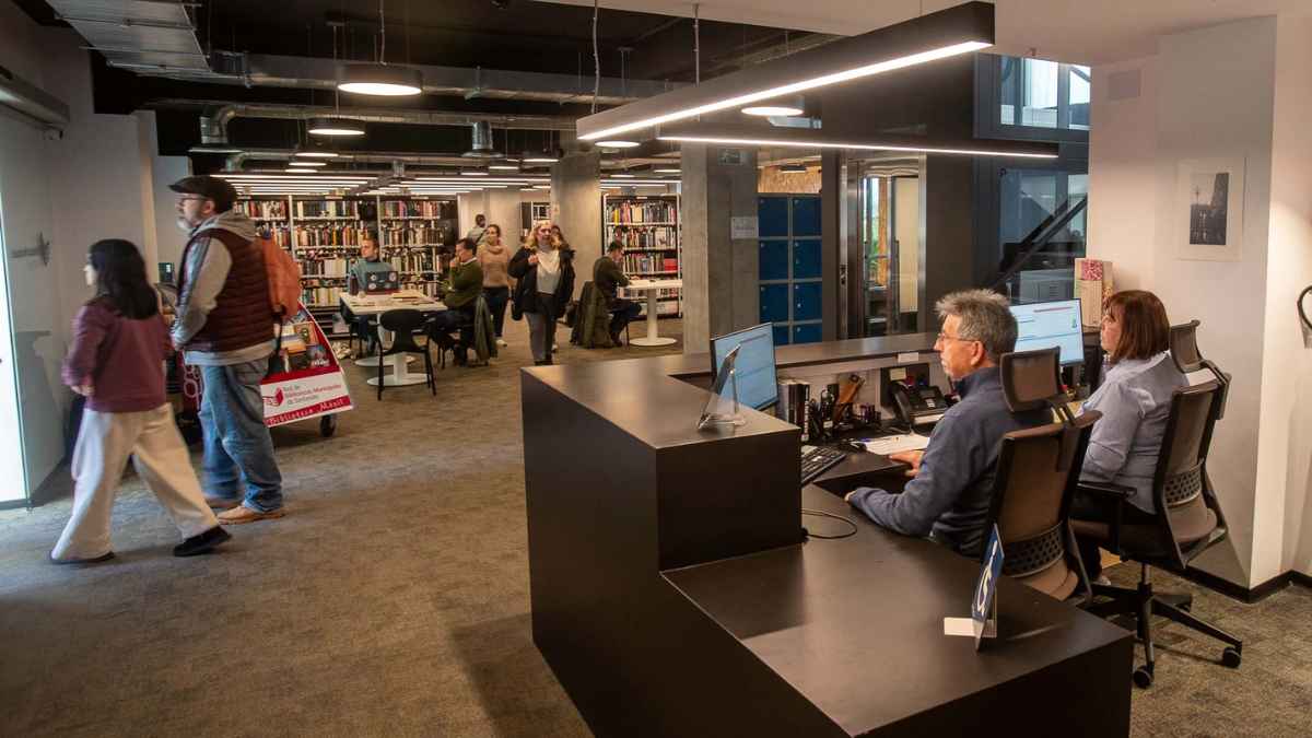 Personas trabajando y atendiendo en una biblioteca pública moderna en España