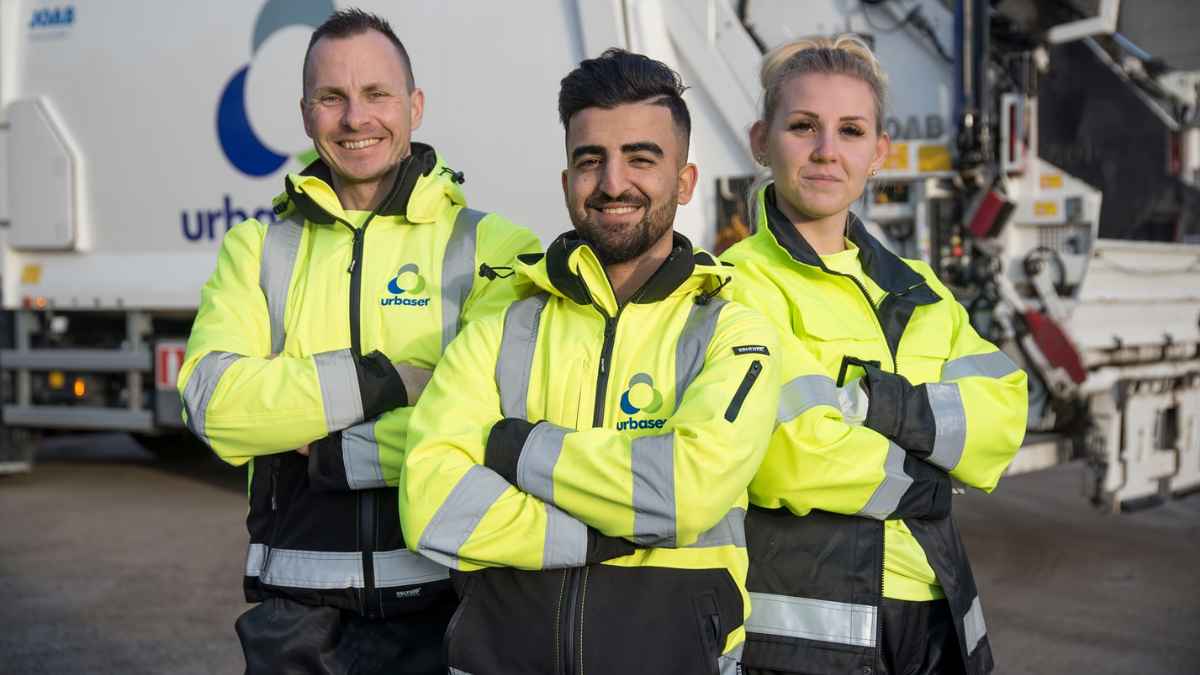 Trabajadores de Urbaser con uniformes de alta visibilidad frente a un camión de recogida