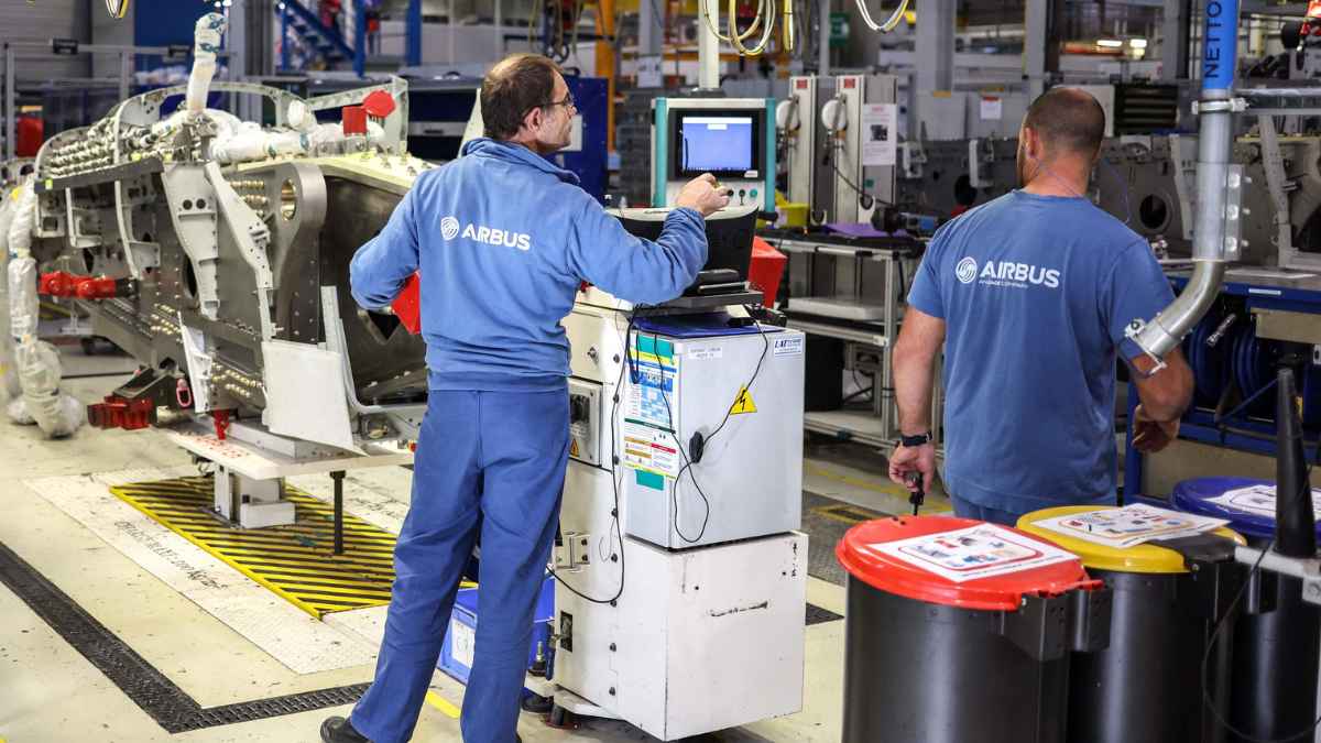 Trabajadores de Airbus operando maquinaria en una línea de producción aeronáutica en España.