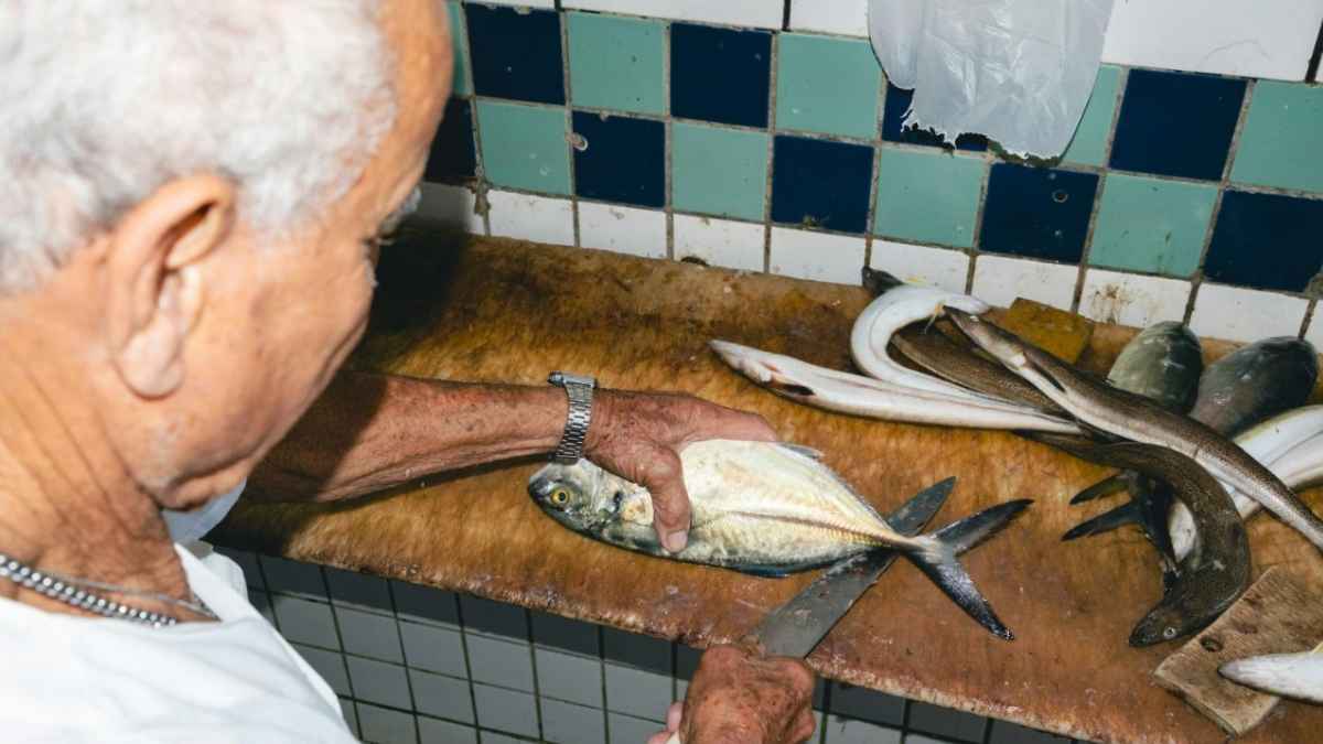 Jubilado ayudando en una pescadería cortando pescado, caso sancionado con 19.000 euros por la Seguridad Social italiana