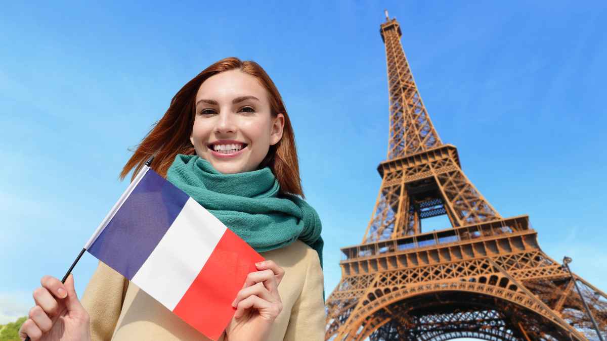 Mujer sosteniendo la bandera de Francia frente a la Torre Eiffel durante un curso online de francés B1-B2