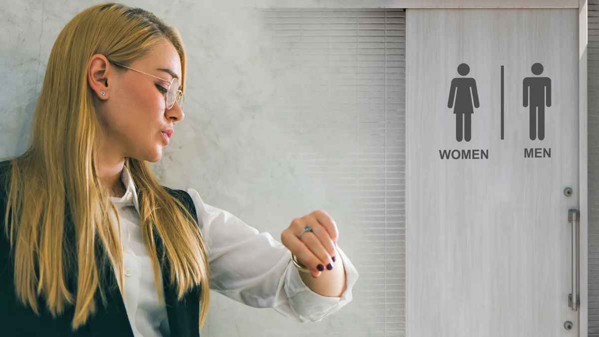 Trabajadora mirando el reloj frente al baño en el trabajo por control del tiempo y despido por pausas prolongadas