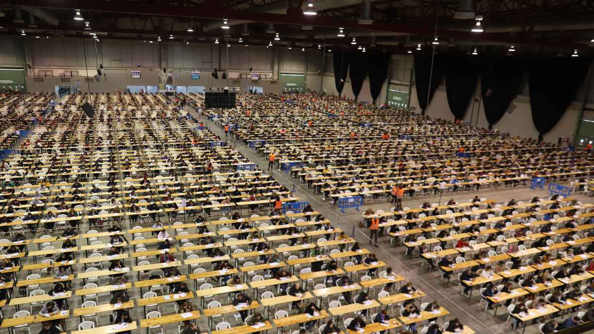 Aspirantes realizando un examen de oposiciones en un gran pabellón con miles de plazas ofertadas