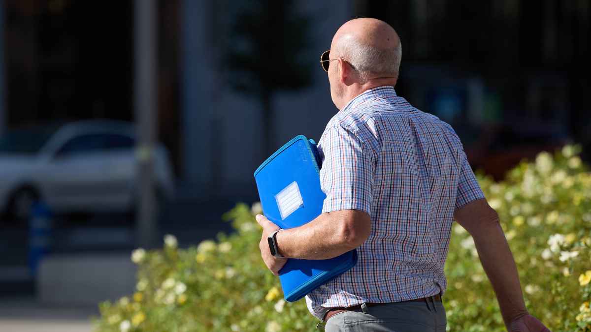 Hombre mayor con carpeta acudiendo a realizar trámites relacionados con la jubilación en la Seguridad Social.