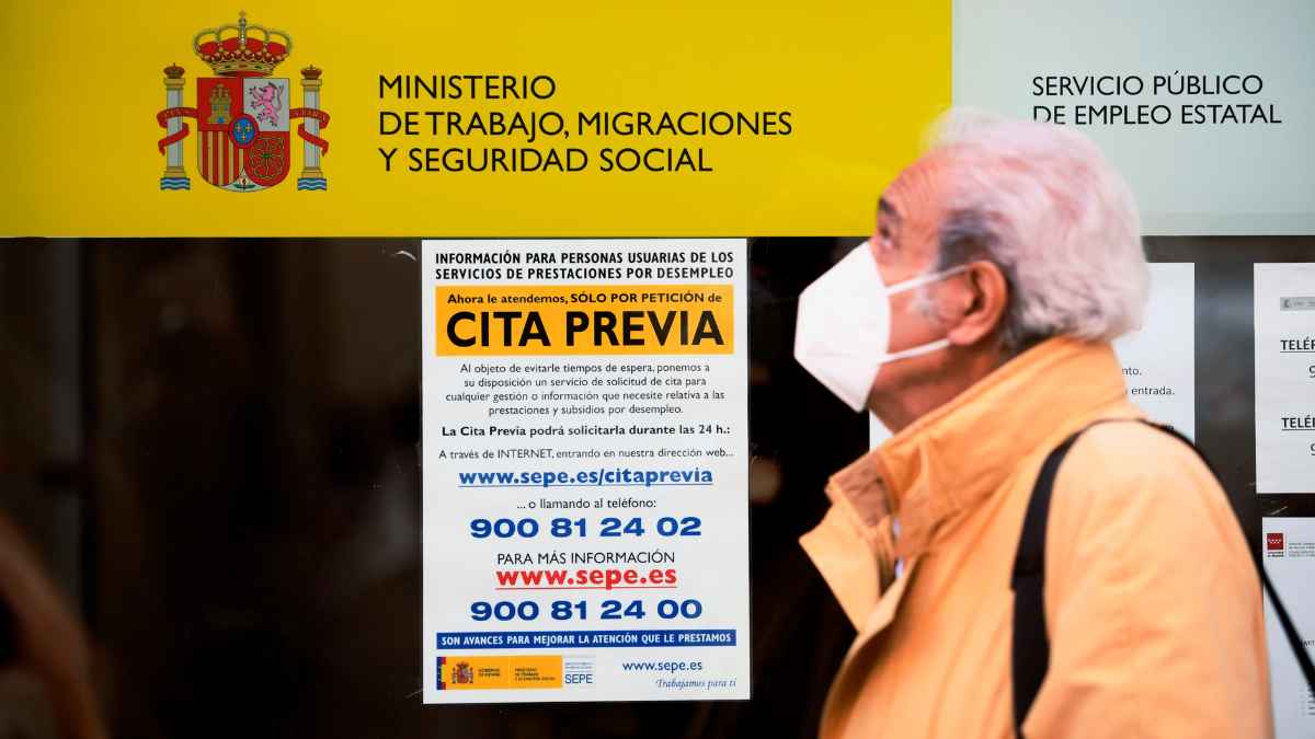 Hombre frente a oficina del SEPE con cartel de cita previa del Ministerio de Trabajo