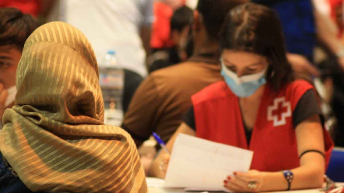 Voluntaria de Cruz Roja atendiendo a personas del programa de refugiados en una mesa de trabajo