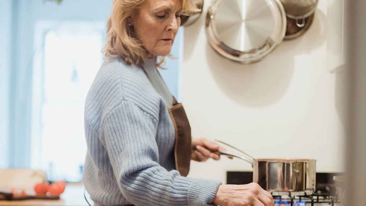 Mujer mayor cocinando en su hogar, ejemplo de ama de casa que puede acceder a la pensión no contributiva